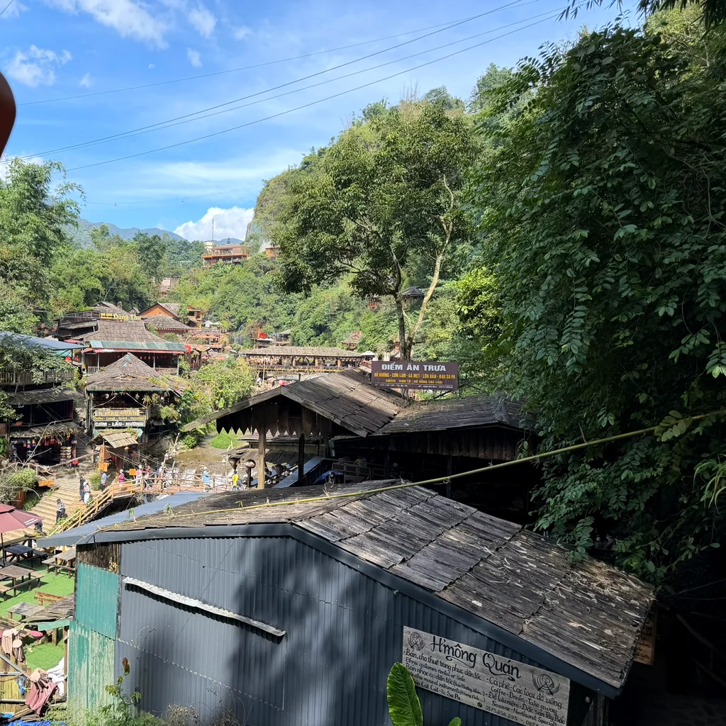 The valley village seen from above Cat Cat Village, with wooden roofs, green forest and people on stone steps