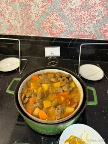 Lamb curry in a green pot with large chunks of potato and carrot