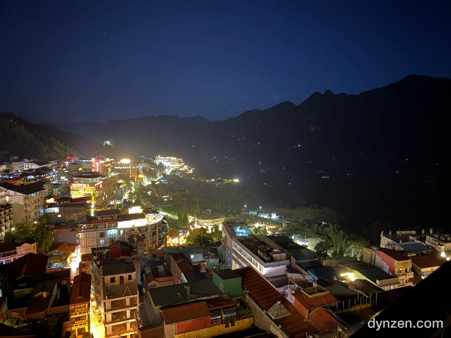 Sapa at night from the 10th-floor open-air terrace, the lit-up town with a dark mountain ridge and stars behind it