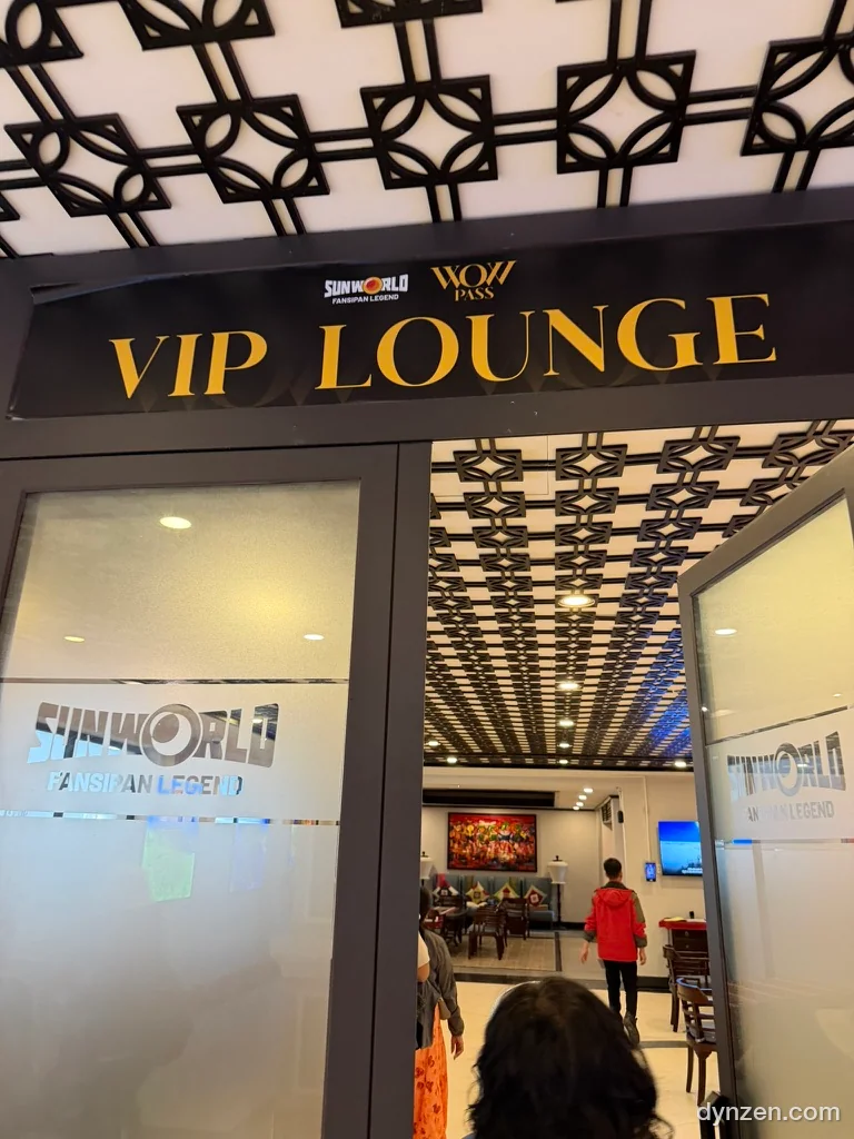 A gold ‘VIP LOUNGE’ sign with the SUN WORLD and WOW PASS logos, and a lounge with sofas behind the glass door