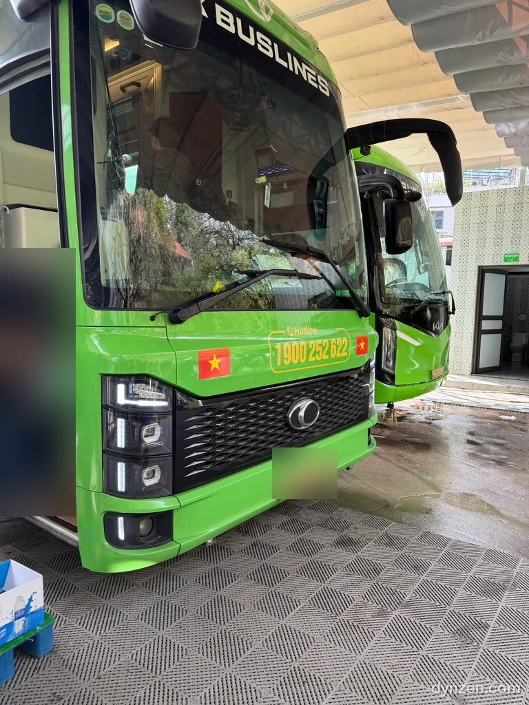 The front of a lime-green HK BUSLINES bus under the office roof