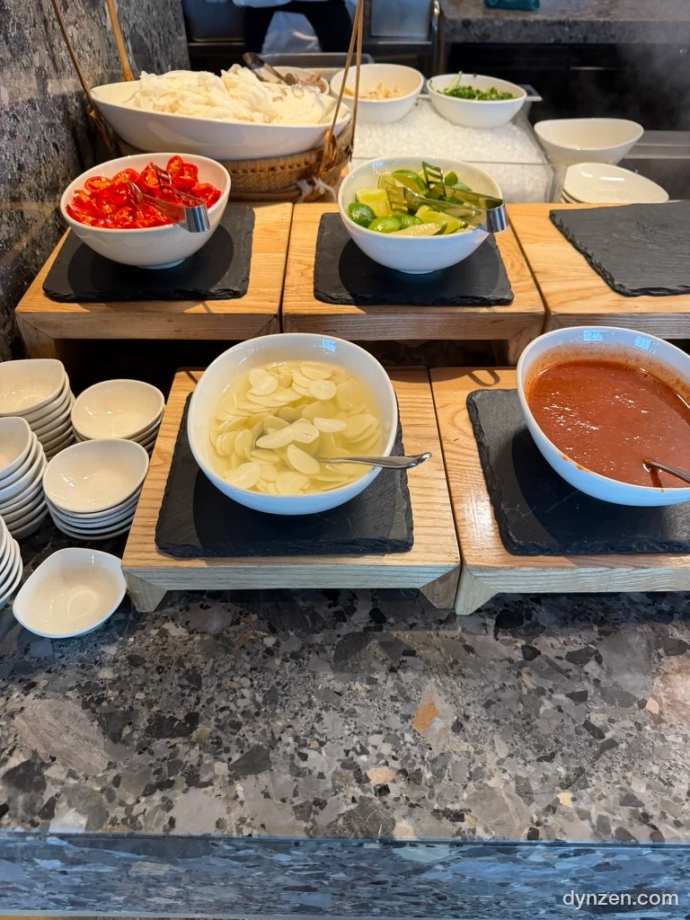 The pho toppings at the L7 West Lake breakfast buffet, bowls of chili, garlic and sauces on a wooden tray