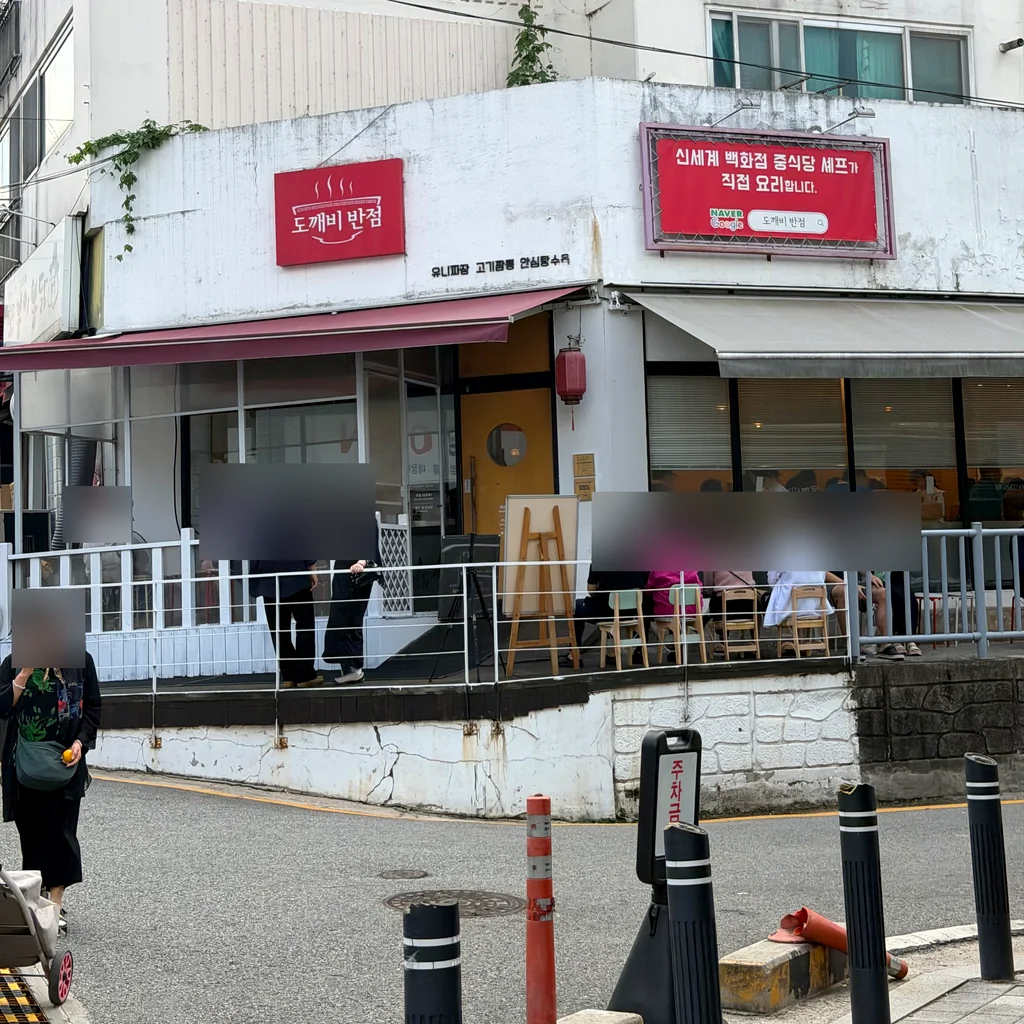 빨간 ‘도깨비 반점’ 간판 아래 테라스 의자에 대기 손님들이 앉아 있는 가게 모퉁이